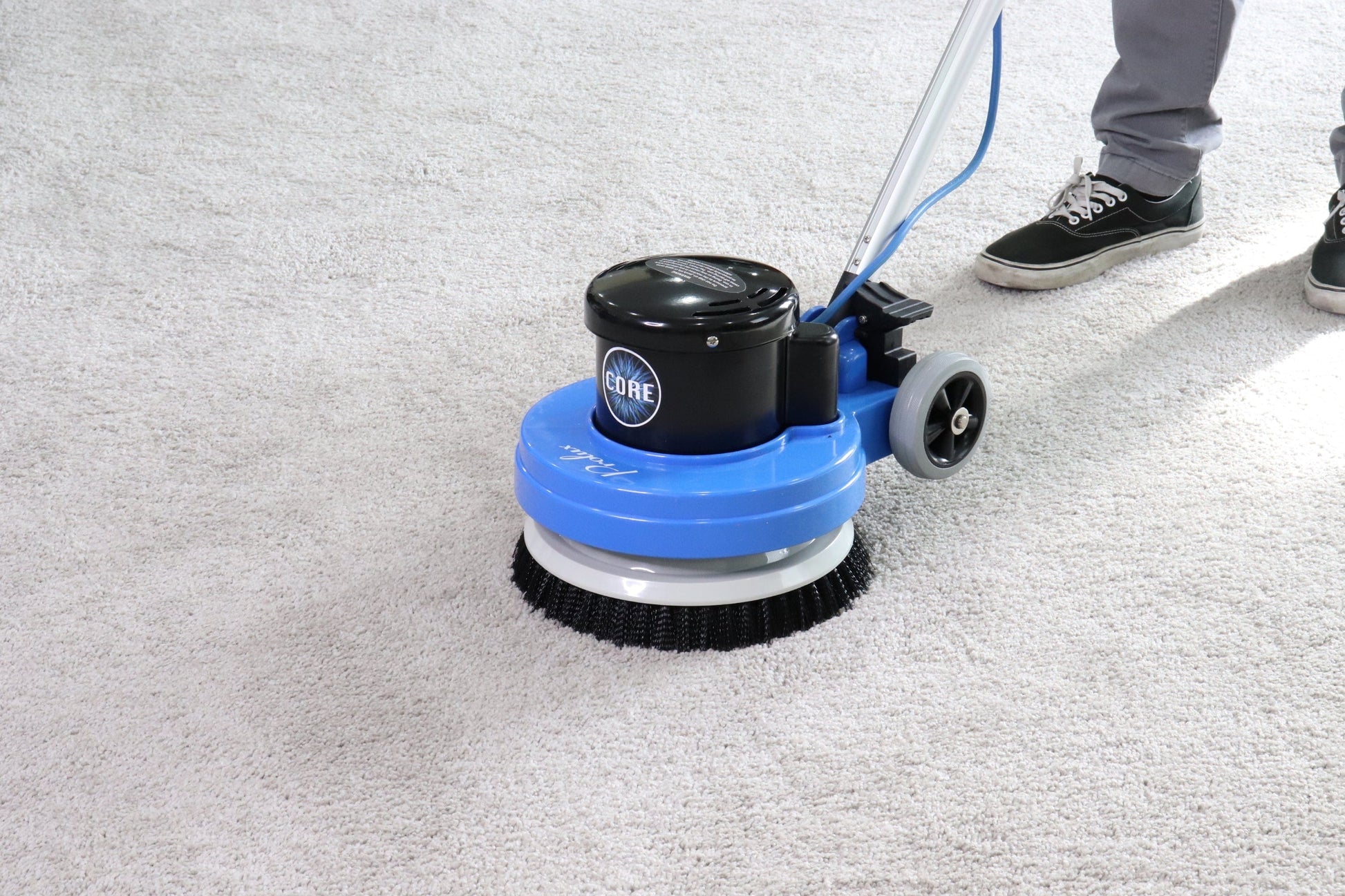 Floor cleaning machine on a concrete floor with a person partially visible.