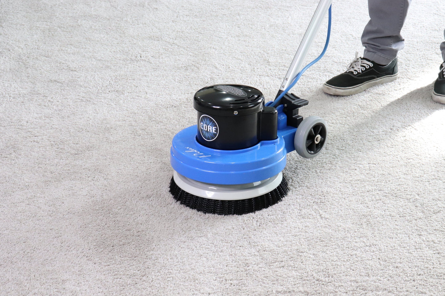 Floor cleaning machine on a concrete floor with a person partially visible.