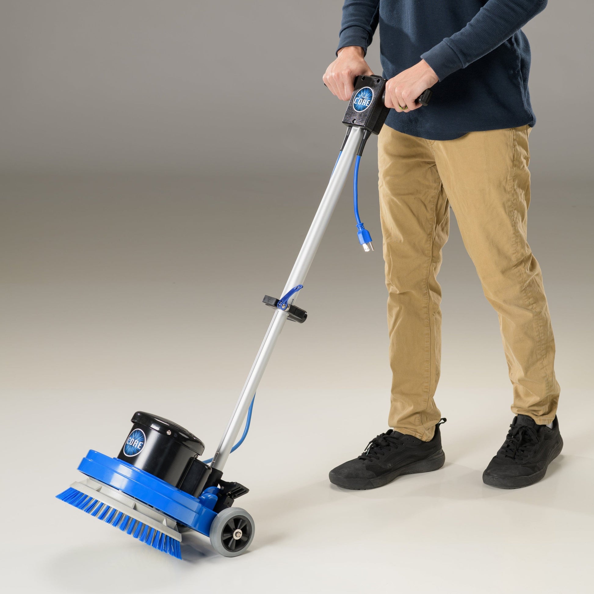 Person using a prolux 13 floor cleaning machine on a plain background