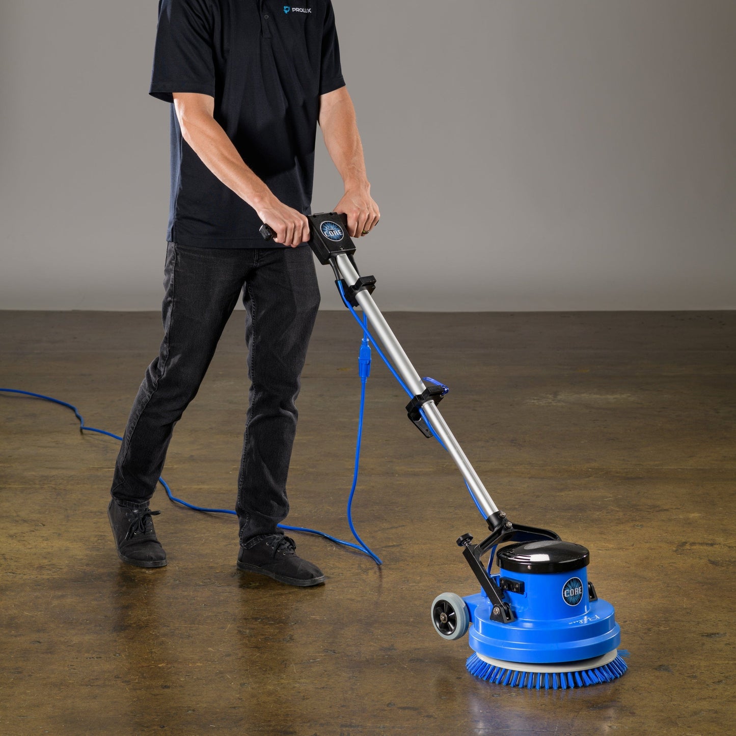 Person using a prolux core 15 floor polisher on a concrete floor with a plain background