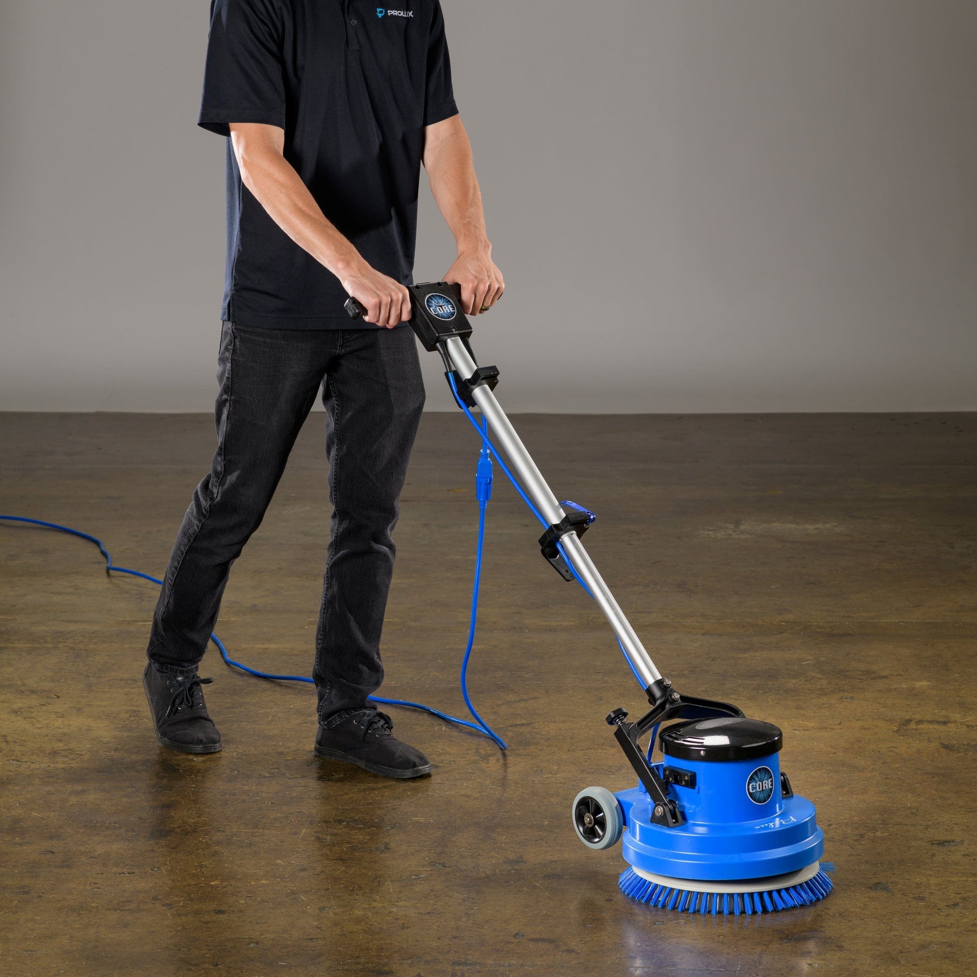 Person using a prolux core 15 floor polisher on a concrete floor with a plain background