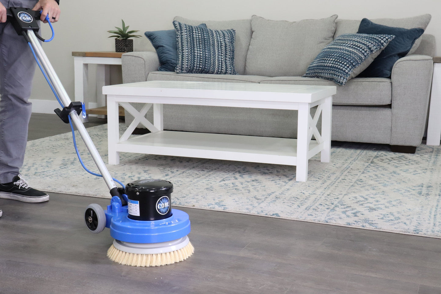Person using prolux 13  floor cleaning machine in a living room with a sofa and coffee table.