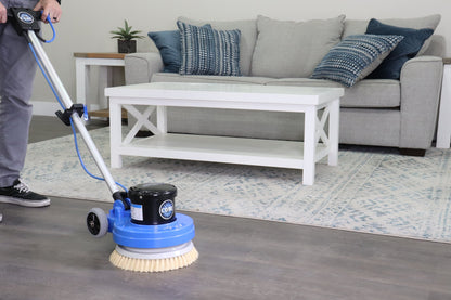 Person using prolux 13  floor cleaning machine in a living room with a sofa and coffee table.
